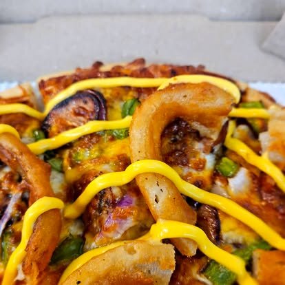 BBQ pizza topped with onion straws and drizzled mustard