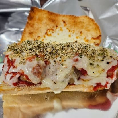 Meatball parmesan sub with melted cheese and Italian seasoning